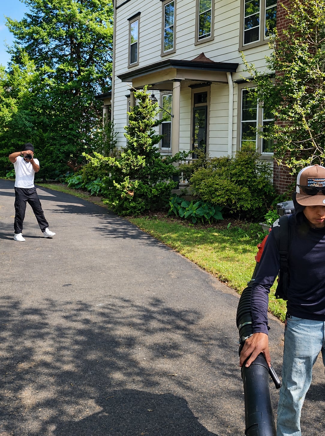 Yvad Brown photographing a lawn care crew member at work in front of a client's home